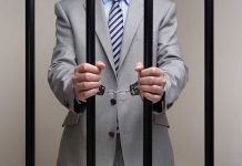 Man Behind Bars Standing And Handcuffed