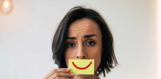 Woman Hiding Pain, Frowning with a picture of a smile in front of her face