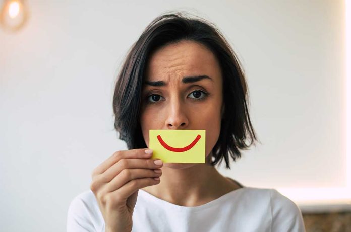 Woman Hiding Pain, Frowning with a picture of a smile in front of her face