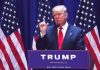 Person speaking at podium with multiple American flags