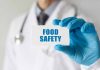 Doctor holding Food Safety card in gloved hand