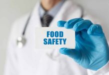 Doctor holding Food Safety card in gloved hand