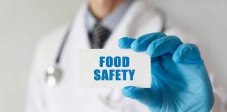 Doctor holding Food Safety card in gloved hand