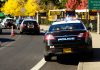 Police cars and school buses on roadside with cones