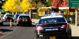 Police cars and school buses on roadside with cones