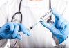 Doctor filling syringe with vaccine from vial