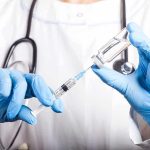 Doctor filling syringe with vaccine from vial