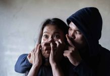Man holding womans mouth gesturing silence