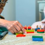 Doctor and patient playing with colorful wooden blocks