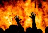 Silhouetted hands raised against a fiery background