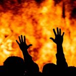 Silhouetted hands raised against a fiery background