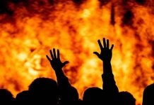 Silhouetted hands raised against a fiery background