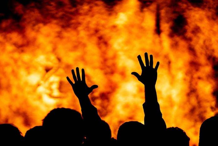 Silhouetted hands raised against a fiery background