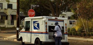 USPS mail carrier at truck near stop sign
