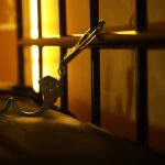 Open handcuffs hanging in dimly lit cell