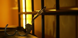 Open handcuffs hanging in dimly lit cell