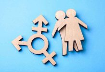 Wooden transgender symbol and couple figures on blue background