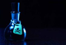 Dark bottle with skull and crossbones label on table
