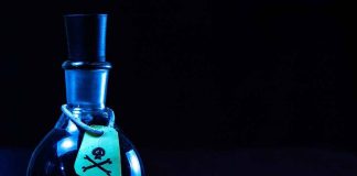 Dark bottle with skull and crossbones label on table