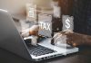 Person typing on laptop with tax-related icons displayed