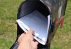 Hand placing mail in a black mailbox