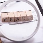 "Fraud" blocks under magnifying glass on invoices.