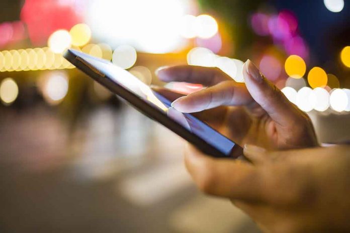 shutterstock_160559990.jpg A person's hand using a smartphone in a city at night with blurred lights in the background