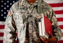 A soldier in a U.S. Army uniform holding books in front of an American flag