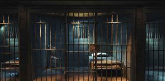 Empty prison cell with metal bars and bed