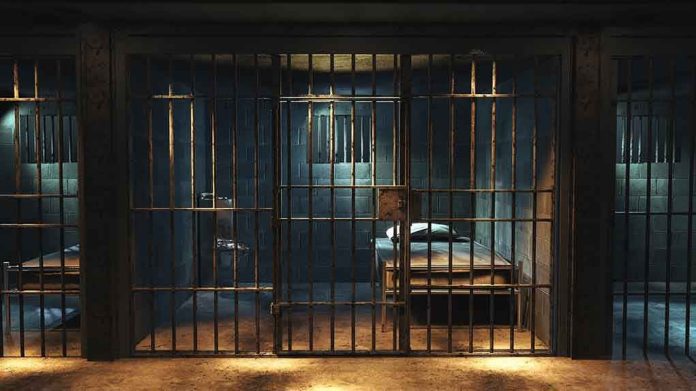 1427252378 Empty prison cell with metal bars and bed