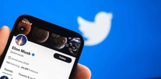 Hand holding phone displaying Twitter profile