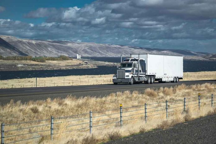 2262168801 Truck driving on rural highway near river and mountains