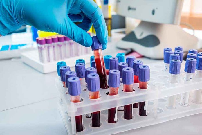 327930536 Gloved hand handling blood samples in a laboratory