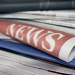Stack of newspapers with NEWS headline visible.