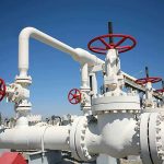 Industrial pipeline with red valves against a clear blue sky