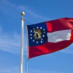 Georgia state flag waving against a blue sky
