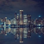 Nighttime view of a city skyline with reflections on water