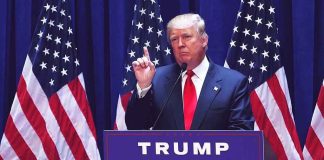 Person speaking at podium with multiple American flags