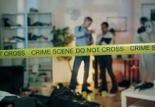 Crime scene with tape and investigators examining evidence
