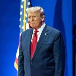 Man in suit next to American flag