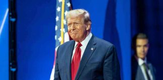 Man in suit next to American flag