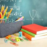 A collection of school supplies including notebooks, a pencil case, and writing instruments on a desk
