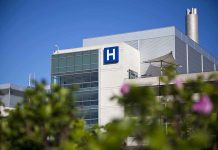 Modern hospital building with a prominent H sign against a clear blue sky
