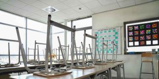 Empty classroom with chairs on top of desks