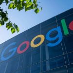 Google logo displayed on a glass building with green leaves in the foreground