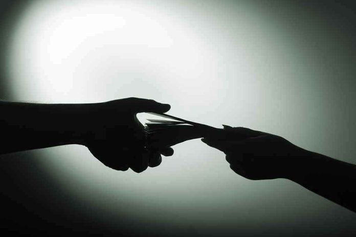1028993377 Silhouette of hands exchanging money in dim light