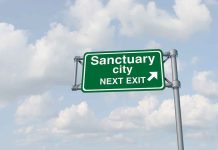 Two Patriots Dead: Sanctuary Policies Under Siege Green road sign saying sanctuary city next exit