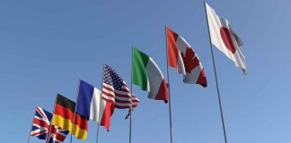 Flags of seven countries against clear blue sky