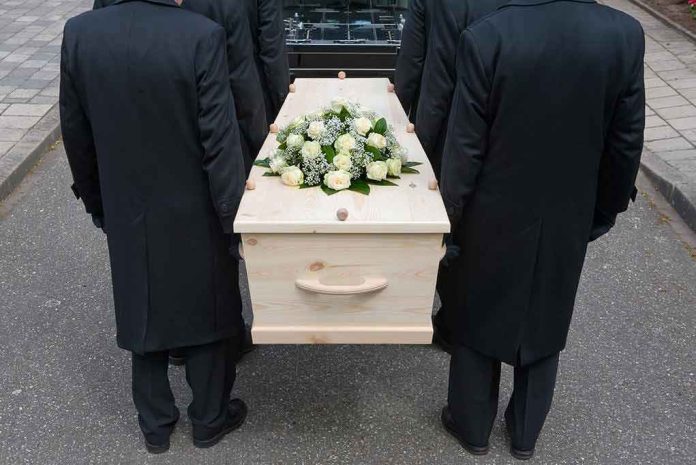 144558722 Four people carrying a coffin with white flowers