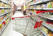Massive Recall STUNS Supermarkets Empty shopping cart in grocery store aisle.